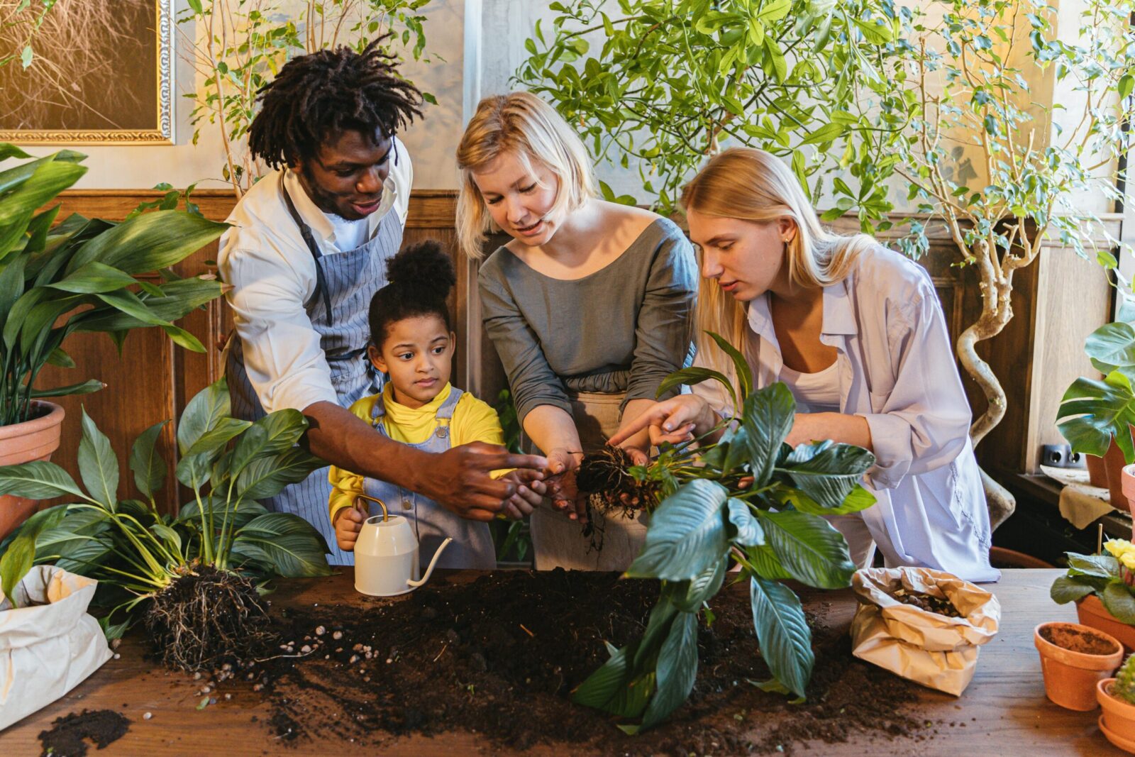 Diverse family gardening indoors, nurturing plants together, enhancing growth.